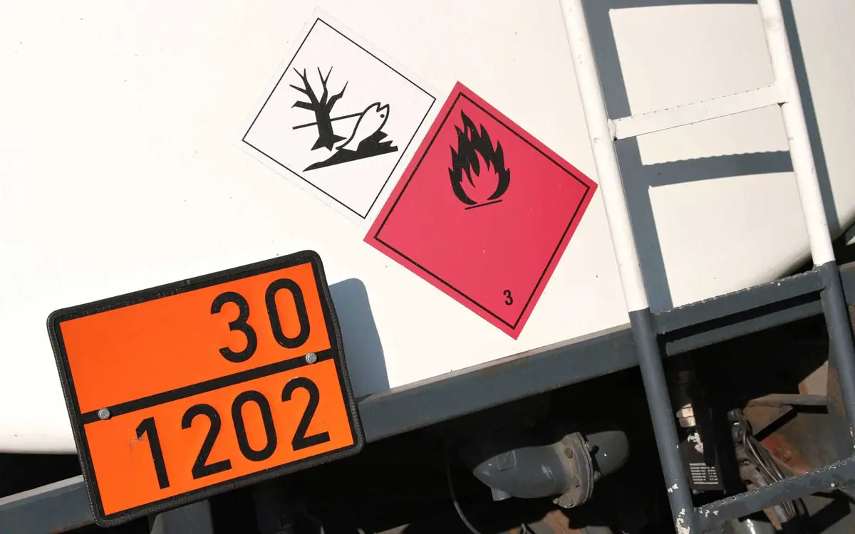 Orange plate with the numbers 30 and 1202 and hazard labels on a vehicle