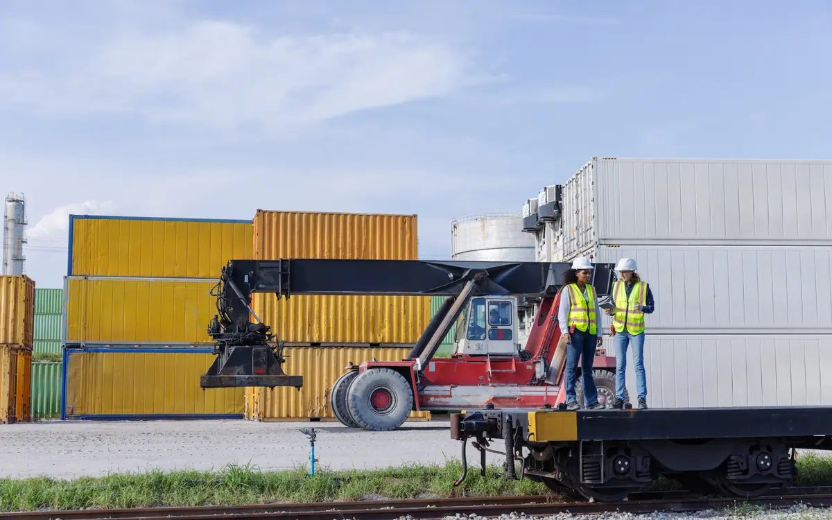 Two specialists watching a container being handled by a reach stacker