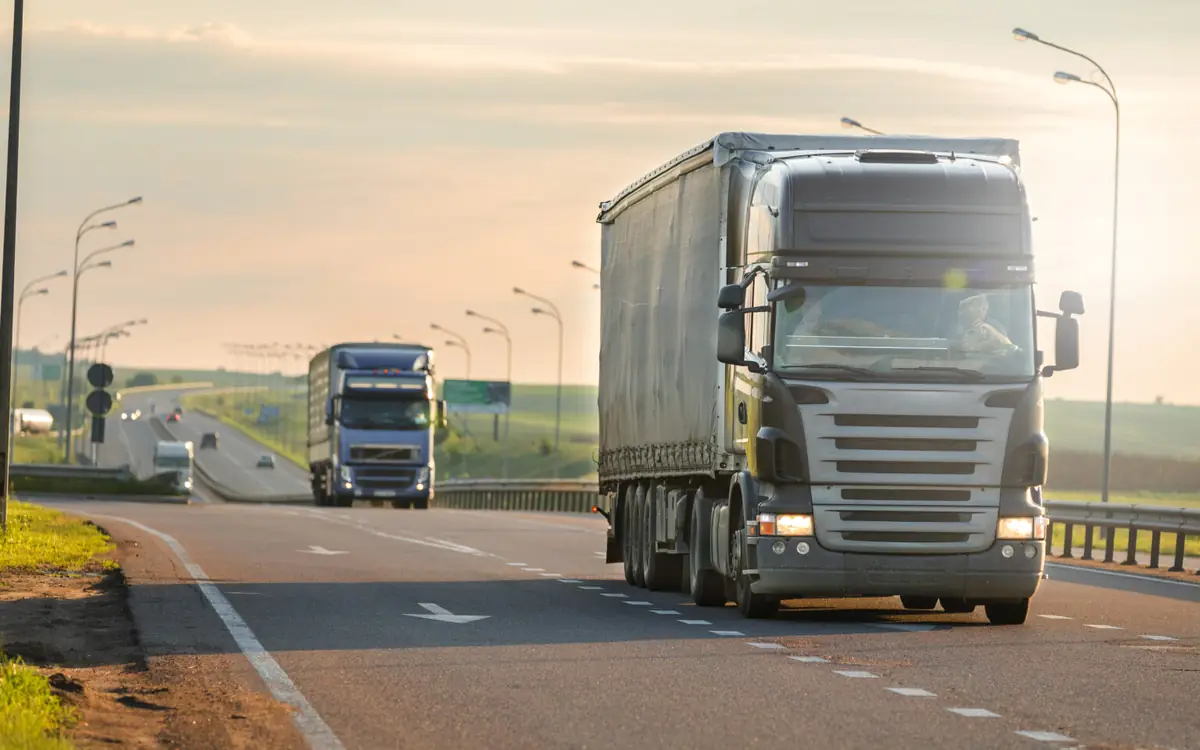 Trucks on a road at sunset