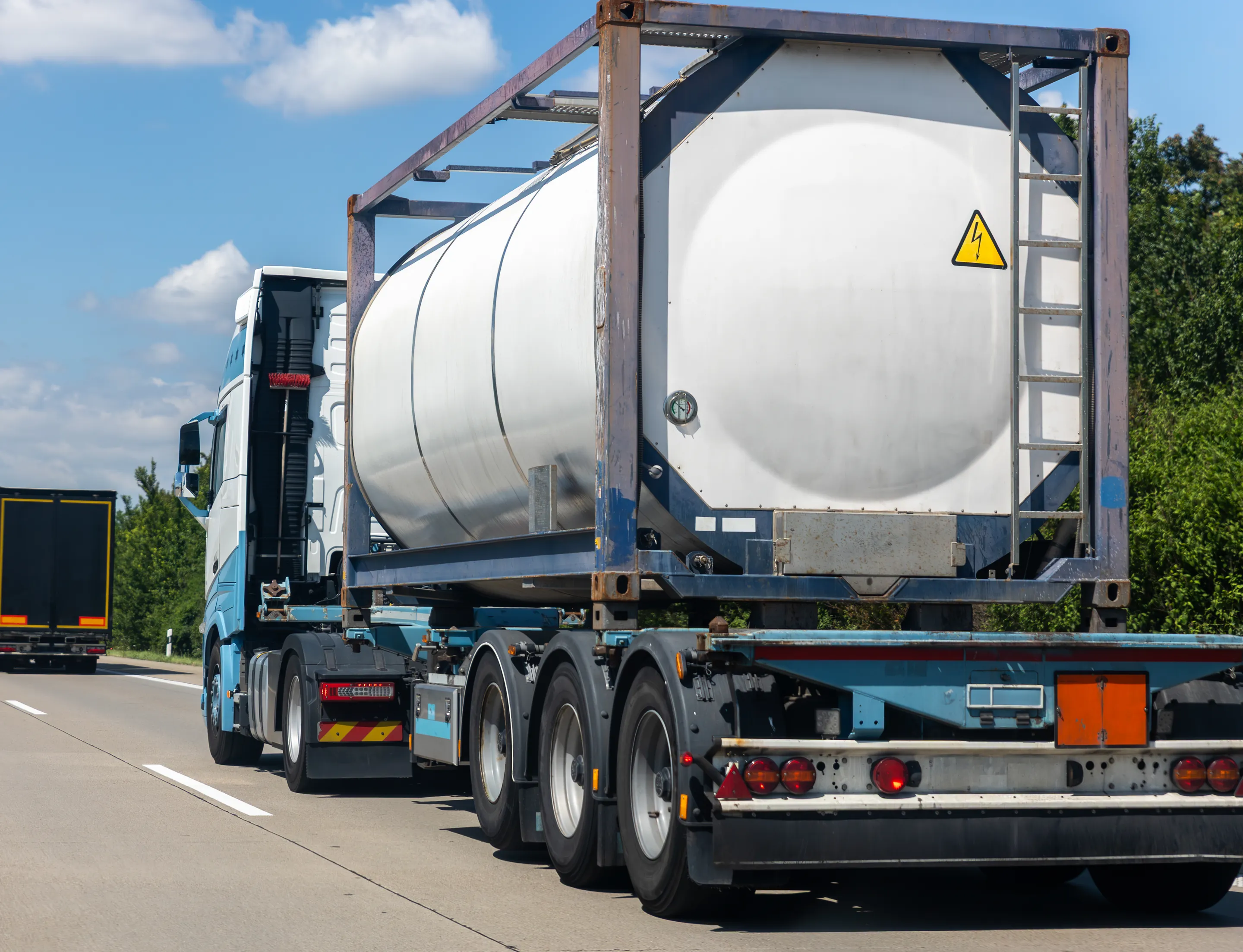 Illustrative photo: a European tractor unit with a tank container on the chassis and an orange ADR plate, on a motorway