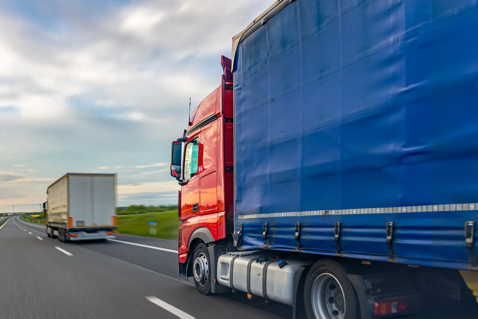 Truck with a blue curtain-sided semi-trailer on the motorway at sunset