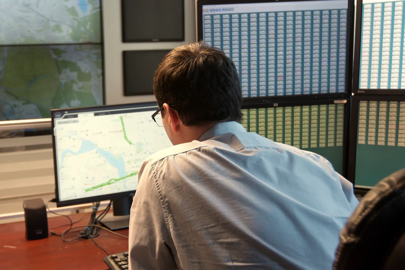 An operator following a route on a map on the monitor, in a dispatch room