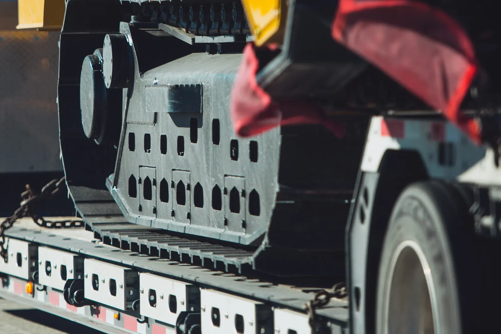 A tracked machine chained down on a low-loader